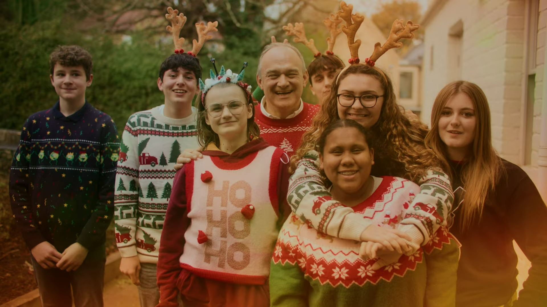 Ed Davey with young carers, everyone is dressed in Christmas jumpers and some people are wearing felt antlers on their head